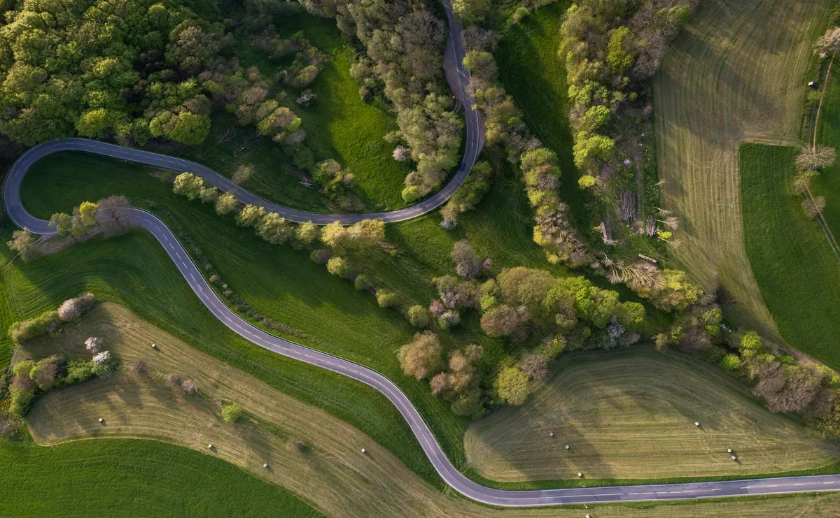 Carretera de curvas entre campos, vista desde el aire