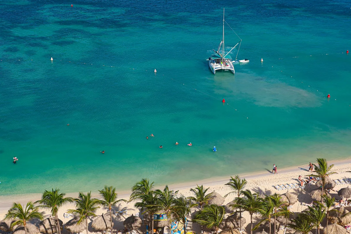 Catamarán fondeado en aguas turquesas junto a la playa